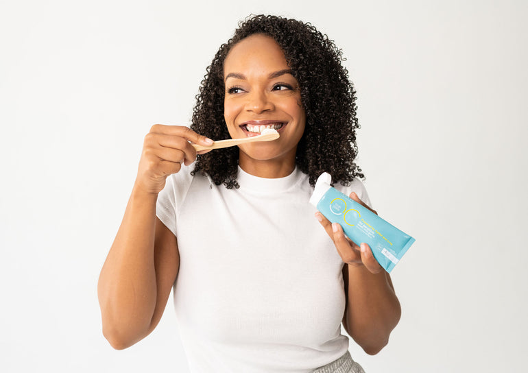 Model brushing teeth holding Toothpaste Tube and Brush